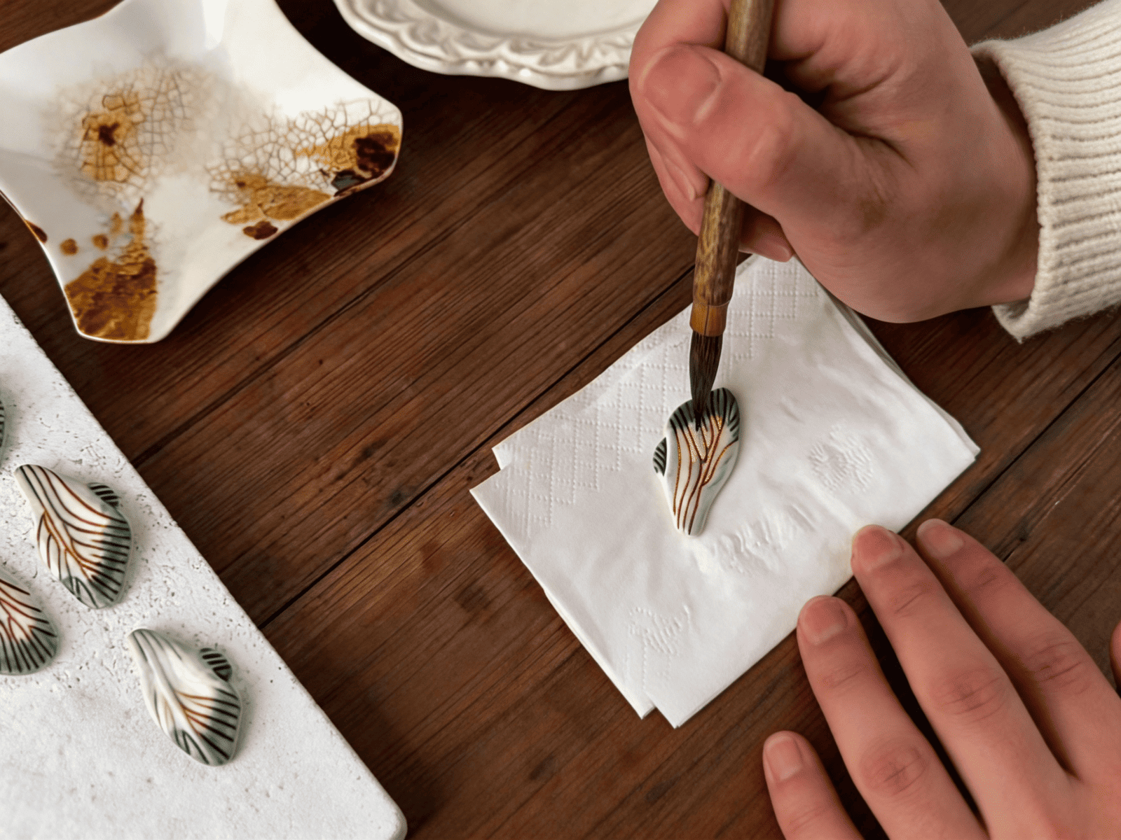 Hand-finishing porcelain jewelry through the ZELIN ART ceramic craft process.