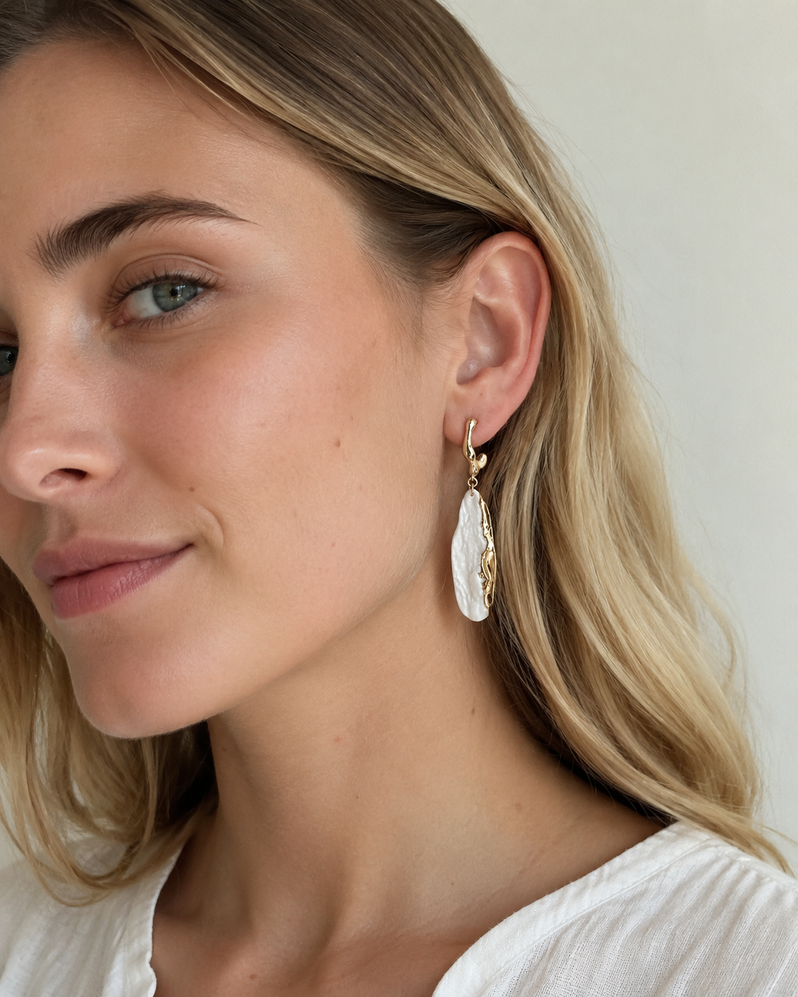 Close-up styling detail of Stone Meets Sea porcelain earrings with ceramic texture and gold accents.